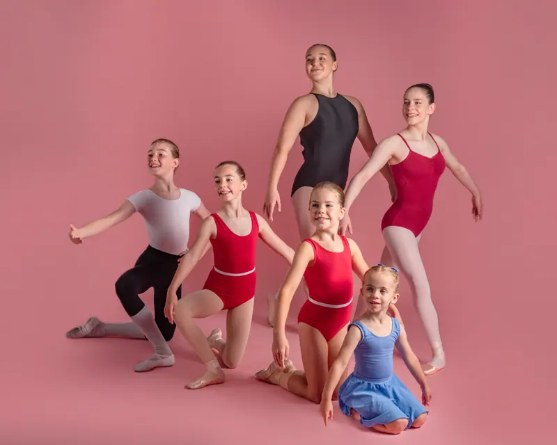 Young dancers posing together in a pink studio